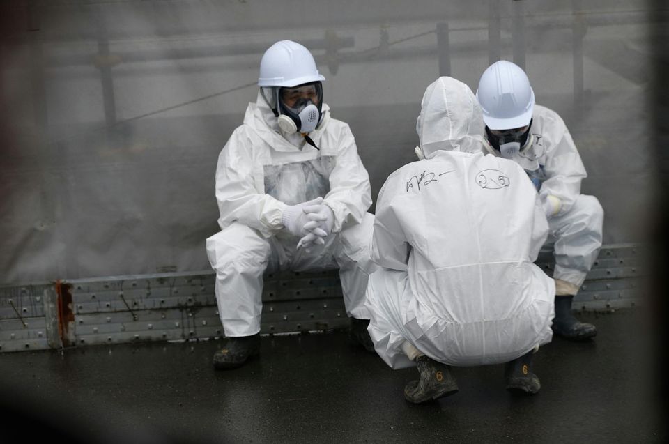 698183-workers-wearing-radiation-protective-gear-rest-on-a-road-at-tepco-s-tsunami-crippled-fukushima-daiic